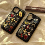 Two black phone cases with decorative pins on a beige surface, with 'rhode' product in the background.
