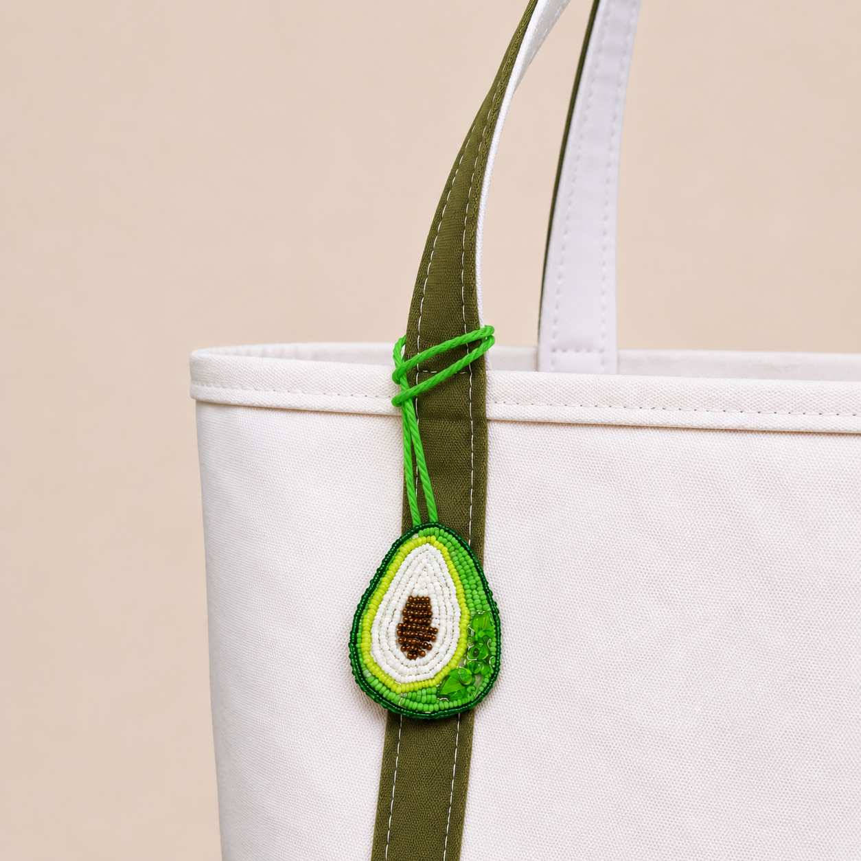 The Avocado hand-beaded bag charm tied to a white tote