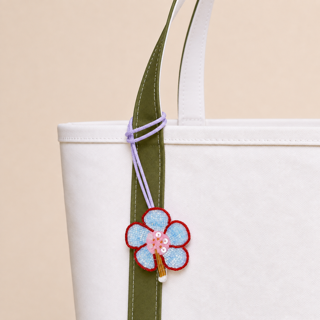 The Bluebell Bloom hand-beaded flower bag charm tied to a white tote