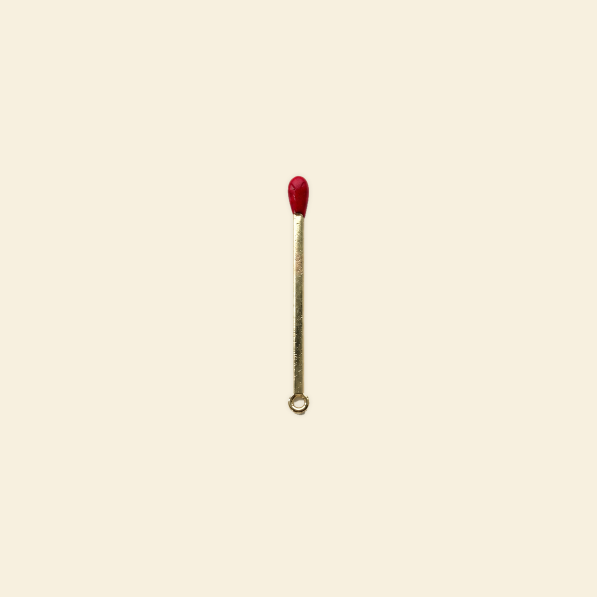 gold matchstick charm on a solid #f7f0df background