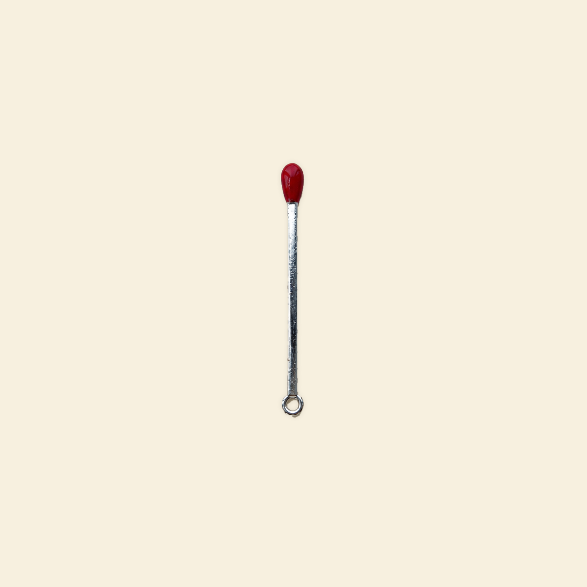silver matchstick charm on a solid #f7f0df background