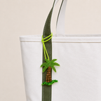 The Palm After Dark hand-beaded palm tree bag charm tied to a white tote