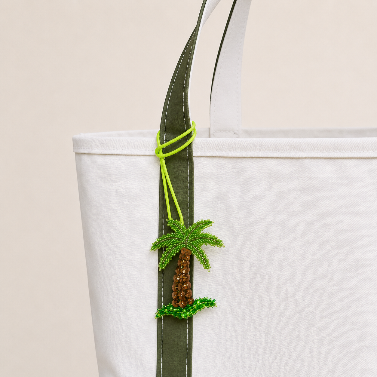 The Palm After Dark hand-beaded palm tree bag charm tied to a white tote