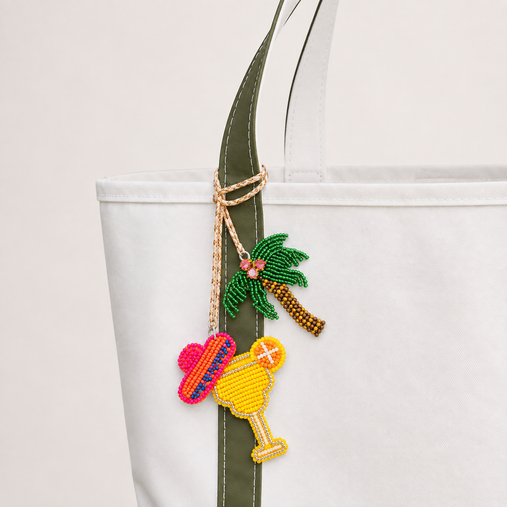 The Palm and Piña Pair hand-beaded bag charm tied to a white tote