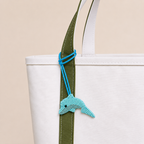The Riviera Dolphin hand-beaded bag charm tied to a white tote